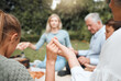 © peopleimages.com - Meal, big family and holding hands to pray at picnic or outdoor feast for gratitude and holiday celebration. Group, nature or people together at lunch with food in garden for thanks, God and grace
