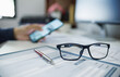 © Lek - close up shot and select focus on eyeglasses, blur background hand of businessman using phone and working with computer, concept looking to the future for success business plan
