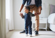 © peopleimages.com - Child, dad and learning to walk in home with mobility development and baby steps with care. Love, support and helping parent with skills, standing and family together in bedroom with holding hands