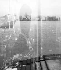 Poster - Monochromatic double exposure of Hong Kong cityscape blending with a silhouette. Water and wooden planks in the foreground create depth and texture in the urban scene.