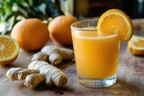 A glass of orange juice with ginger root and orange slices on a wooden surface in soft lighting