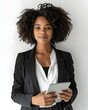 © Banstanks - Confident young woman in a sleek blazer holding a tablet, standing against a minimalist background