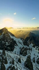Fototapete - A majestic mountain peak with a sun shining brightly in the sky. The mountain is covered in a thick layer of snow, giving it a serene and picturesque appearance