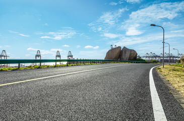 Aufkleber - Empty road near shipping port and rock under blue sky. Travel background.