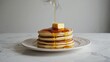 © Alla - A plate of fluffy pancakes with warm syrup being poured on top