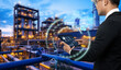 © panuwat - Smart industry 4.0 mangement control system concept.Hands holding tablet on blurred Chemical plant refinery industrial equipment as background