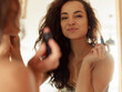 © Nataliya - Close up of happy young Caucasian pretty lady looking in the mirror indoors putting makeup on face. Smiling attractive female using lipstick cosmetic. Leisure, beauty concept