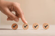© New Africa - Approved. Woman touching wooden circle with check mark on beige background, closeup