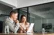 © insta_photos - Two professional executives discussing financial accounting papers working with paperwork in office. Mature business woman and man managers holding legal corporate documents at meeting. Copy space.