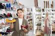© JackF - Positive female customer choosing pair of shoes in shoe store