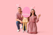 © Pixel-Shot - Happy family in bunny ears holding paper Easter egg on pink background