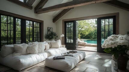 Poster - Cozy living room with white plush seating dark framed windows wooden beams and doors opening to greenery and a pool with white flower arrangements