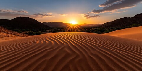 Aufkleber - Golden hour landscape view showcasing desert dunes hills and radiant sun setting over distant mountains casting light on the textured sand formation