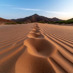 Aufkleber - Footprints in Textured Sand Dunes Leading to Mountainous Horizon under Blue Sky and Warm Sunlight
