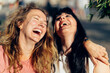 © Carlo Prearo - Two happy women laughing together outdoors in the city