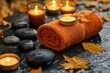 © Sarinya - Serene spa ambiance with orange towel smooth stones and flickering candles creating a relaxing atmosphere for wellness and tranquility