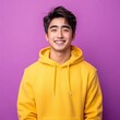 © Sarinya - Cheerful young man in yellow hoodie smiles brightly against vibrant purple background creating a modern portrait