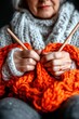 © yuliachupina - Knitting a vibrant orange blanket indoors during a cozy winter afternoon
