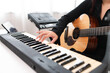 © PhugunStock - Beautiful Asian teen girl playing guitar, composing music in home recording studio using computer, headphones, condenser microphone, tablet and keyboard for mixing and mastering music.