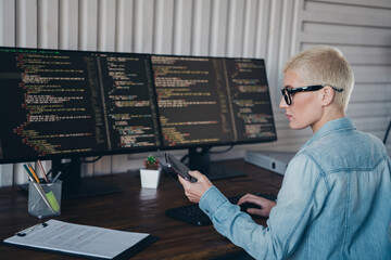 Focused female coder working on software development in a modern home office setting with multiple monitors