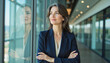 © f_bossa - Modern portrait headshot of a friendly ceo executive business worker: A confident businesswoman with graying hair stands with her arms crossed, gazing thoughtfully out of a large window in a modern