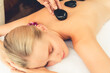 © InfiniteFlow - Hot stone massage at spa salon in luxury resort with day light serenity ambient, blissful woman customer enjoying spa basalt stone massage glide over body with soothing warmth. Quiescent
