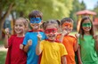 © Pete - Group young kids dressed superhero costumes with capes, masks posing in park. Cheerful elementary school students smile, show thumbs up. Happy children enjoy game, fun outdoors.