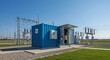 © LittleDuck - Modern Electrical Substation Container - A blue shipping container houses electrical equipment at a modern substation, featuring high-voltage power lines and transformers in the background