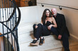 © Mat Hayward - Attractive middle aged couple sitting together on an elegant spiral staircase. The man and woman are fashionable. The male is bald with a beard and the female person is wearing a jump suit for fashion