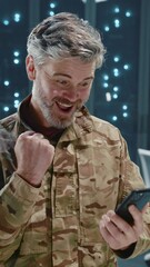 Wall Mural - cheerful bearded soldier using mobile phone messaging receiving good news at data center coworking s