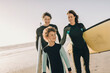 © Marko Geber - Young family of surfers walking on a beach getting ready to go surfing together on their holiday vacation