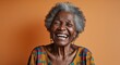 © sevenSkies - black African elderly woman on orange plain bright background happy laughing hysterical looking at camera portrait banner with copy space ad concept marketing
