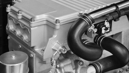 Aufkleber - A black and silver engine with a black hose attached to it. The hose is connected to a black pipe