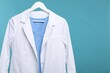 © New Africa - Doctor's coat on hanger against blue background. Space for text