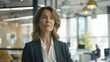 © Lumara Studio - Confident middle-aged Caucasian businesswoman standing in modern office with glass walls, wearing formal attire, thoughtful expression, leadership and determination in professional setting