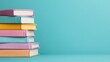 © Kaminashi Nozomi - Stack of colorful books against a teal background