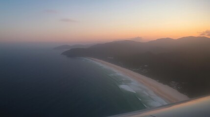 Wall Mural - a stunning aerial view of a beach during sunset with waves and mountains in the background.