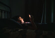 © Cavan Images - Teen boy in bedroom using smartphone while laying on his bed at night.