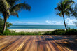 © TheseusStock - Wooden floor with a beautiful beach and palm tree background, a panoramic banner for a summer vacation concept.