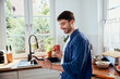 © baranq - Man in kitchen having coffee while using his mobile phone