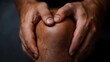 © Aazish Imago - Close-up of a pair of hands holding a knee, emphasizing care and attention for a male individual's joint.
