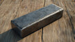 © Andrew - Refined Metal Block on Wooden Surface: A striking close-up showcases a solid, rectangular block of refined metal casting a defined shadow on a textured wooden surface, representing strength, quality.