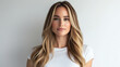 © Keopaserth - beautiful woman with long, flowing hair stands confidently against neutral background, wearing simple white t shirt that enhances her natural beauty and serene expression