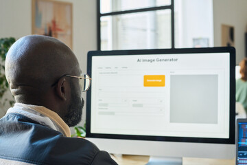 Fototapete - Focus on bald head of young African American designer sitting in front of desktop computer monitor and using AI image generator