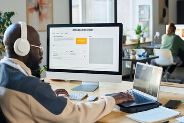 Poster - Young serious man in headphones pressing keys of laptop and desktop computer keypads while working over new software
