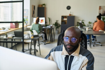 Poster - Bald African American software developer looking at screen of desktop computer while testing new product or decoding data