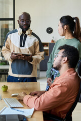 Aufkleber - Young African American programmer with tablet in hands looking at his colleagues during discussion of new software