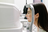 Examination of eyes of patient using optical coherence tomograph. Ophthalmologist is scanning cornea of girl patient. Optical coherence tomography OCT scan to create pictures of the back of eye.