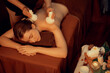 © InfiniteFlow - Hot herbal ball spa massage body treatment, masseur gently compresses herb bag on woman body. Tranquil and serenity of aromatherapy recreation in warm lighting of candles at spa salon. Quiescent