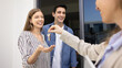 © fizkes - Latin couple receiving keys from their first house, feel happy of purchasing new own apartment or flat. Real estate agent handing over house keys to smiling newlyweds spouses. Moving, start new life